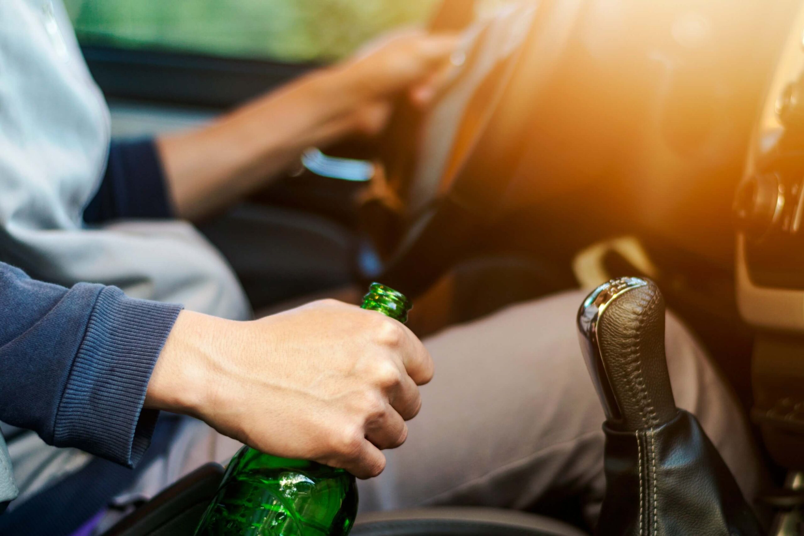 Man holding alcohol bottle drinking alcohol while driving a truck