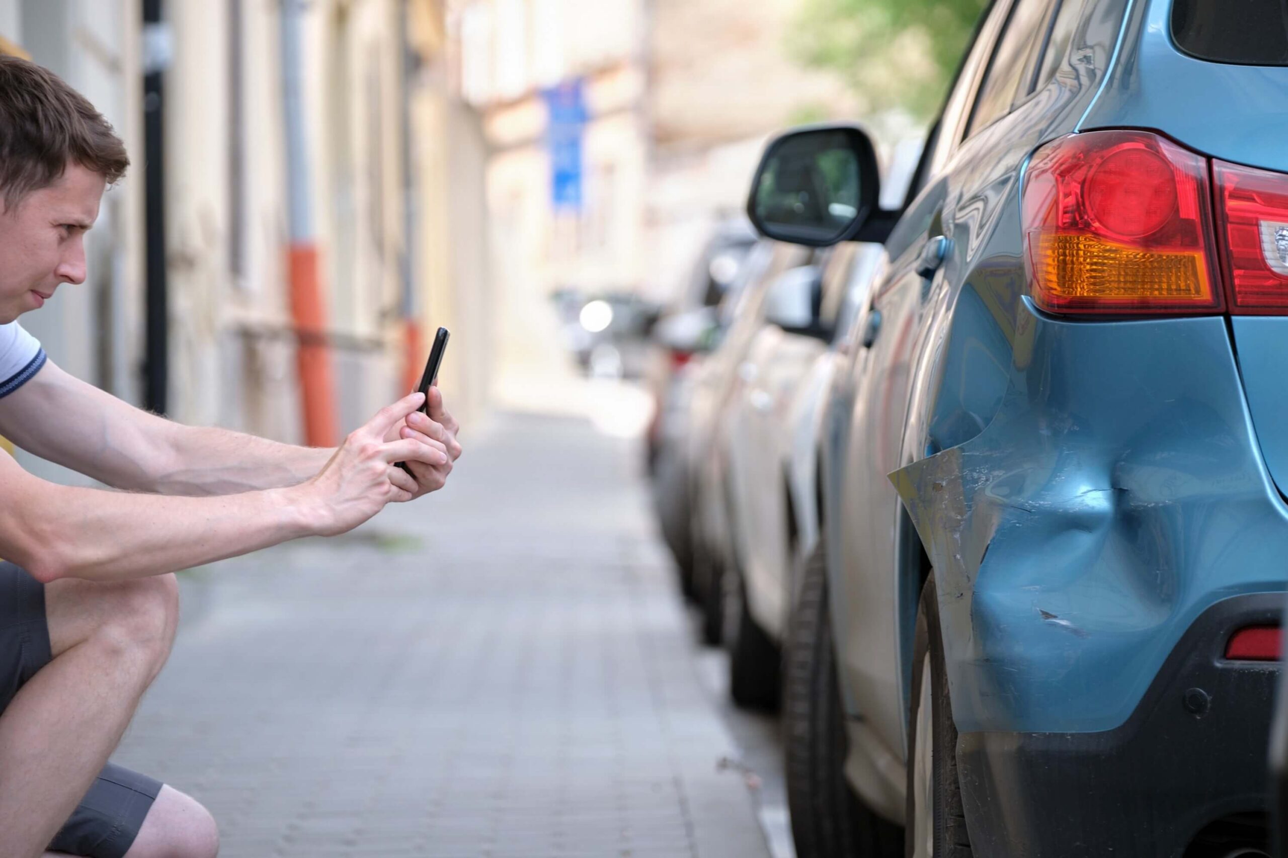 Stressed driver taking photos with car camera phone of wrecked vehicle