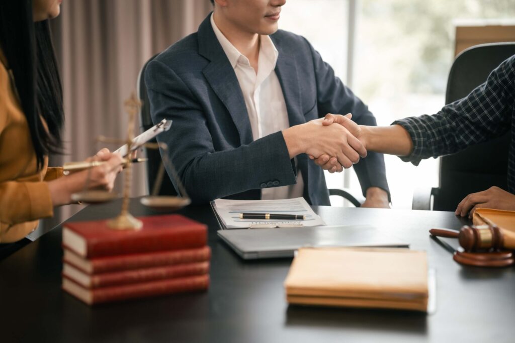 Handshake with legal scales and books visible on a desk