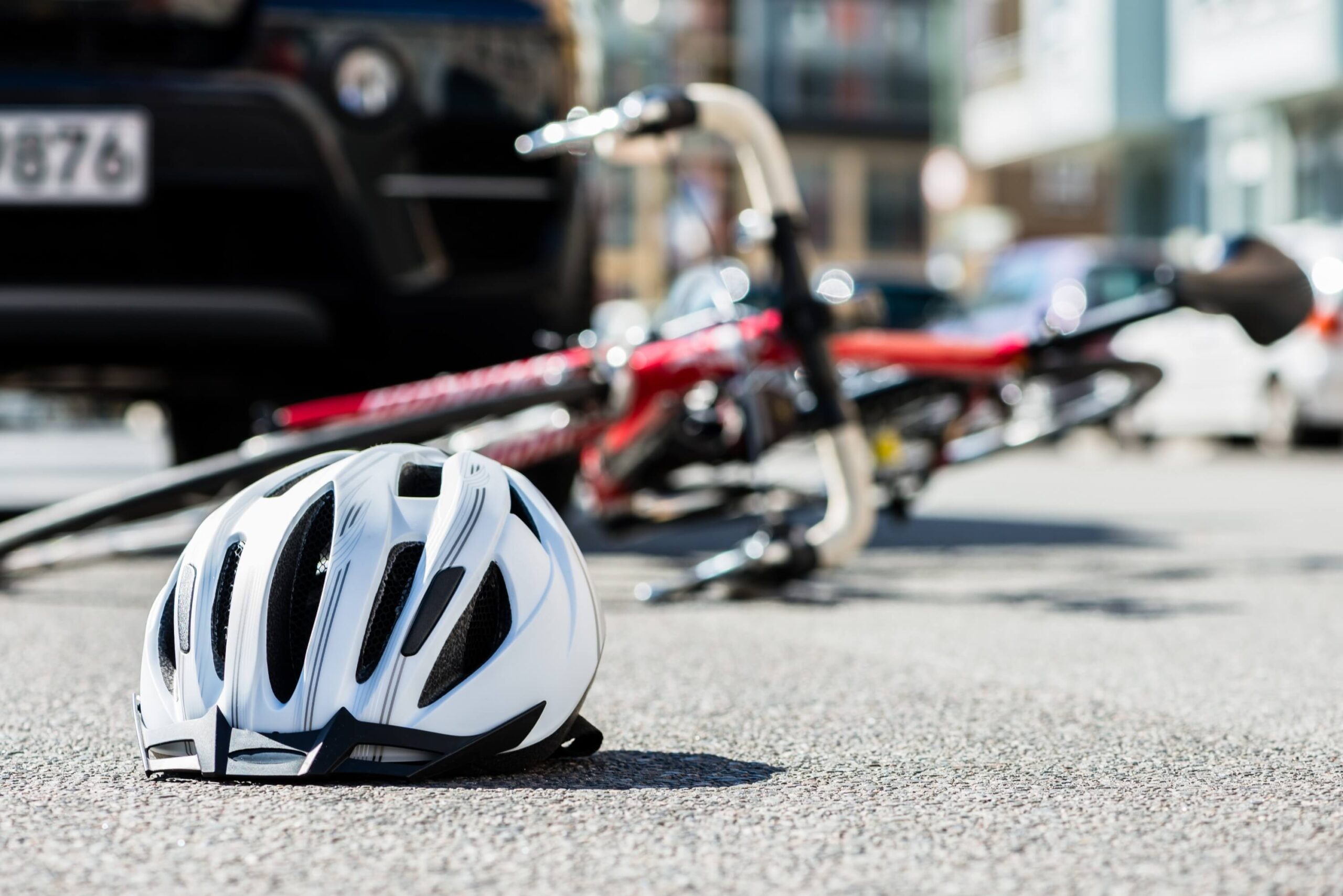 Close-up of a fallen bicycle helmet on the asphalt next to a bicycle after a truck accident on the city street