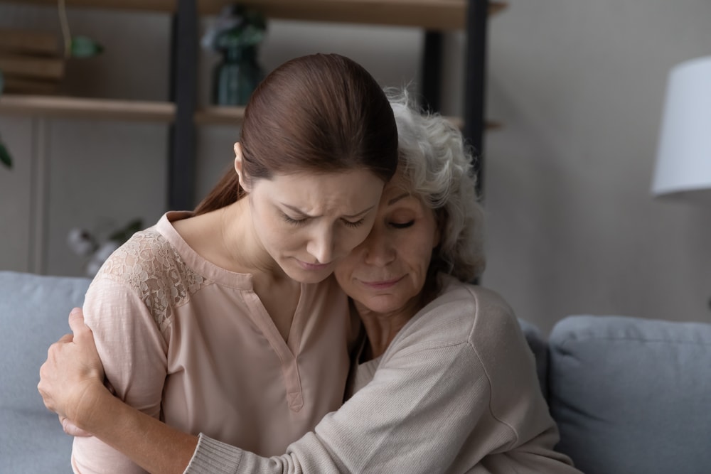 Aged retired female mother hold in arms embrace tight upset depressed young female adult kid daughter listen to confession give excuse for wrong deed. Old lady mom support comfort beloved grownup girl